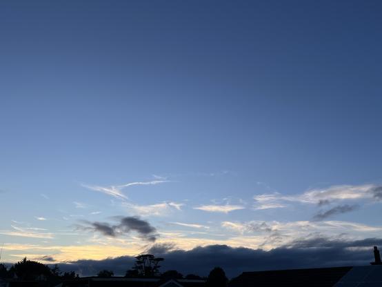 Mostly clear blue sky, some yellow at the bottom and some wispy cirrus and thicker stratus near the horizon 