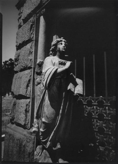 A black and white pinhole photo of an angel statue in Mountain View cemetary in Oakland