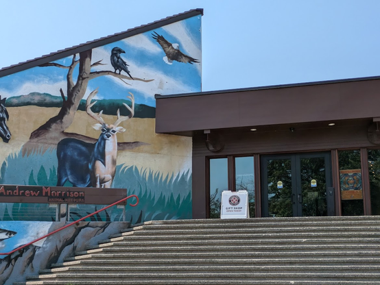 One of several entrances of Daybreak Star, with a very tall mural showing regional animals including an elk, a crow, an eagle.