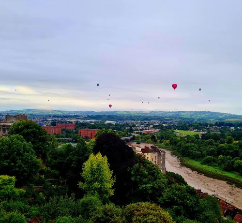 A high view of Bristol facing south with about 10 balloons in the sky.