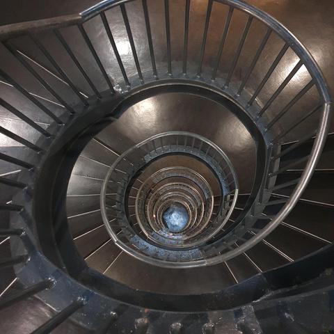 A dark staircase, spiraling down. Photo made looking down into the middle. 
