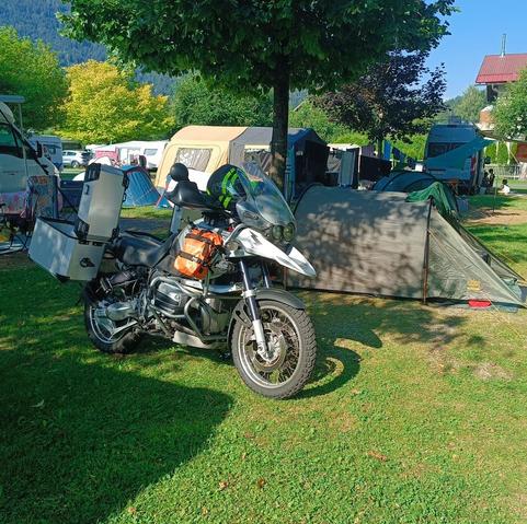 Ein Motorrad vor einem Zelt auf einem Campingplatz.