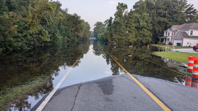 Flood over Chief of Love Road, isolating the community of Teal Lake, just beyond the flood water. Glassy calm waters. Flooding from TS Debby