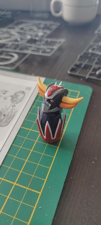 Tête de Goldorak sur un élément de bras. 
Fond : travail et grappes de gunpla