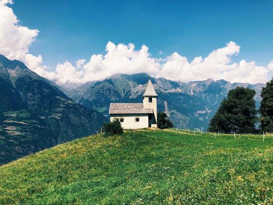 A tiny old church on the top of a hill in the mountains