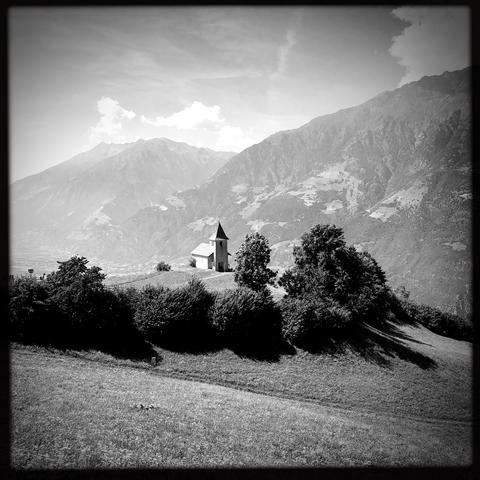 Una chiesetta su una collina in montagna e le cime delle montagne in lontananza