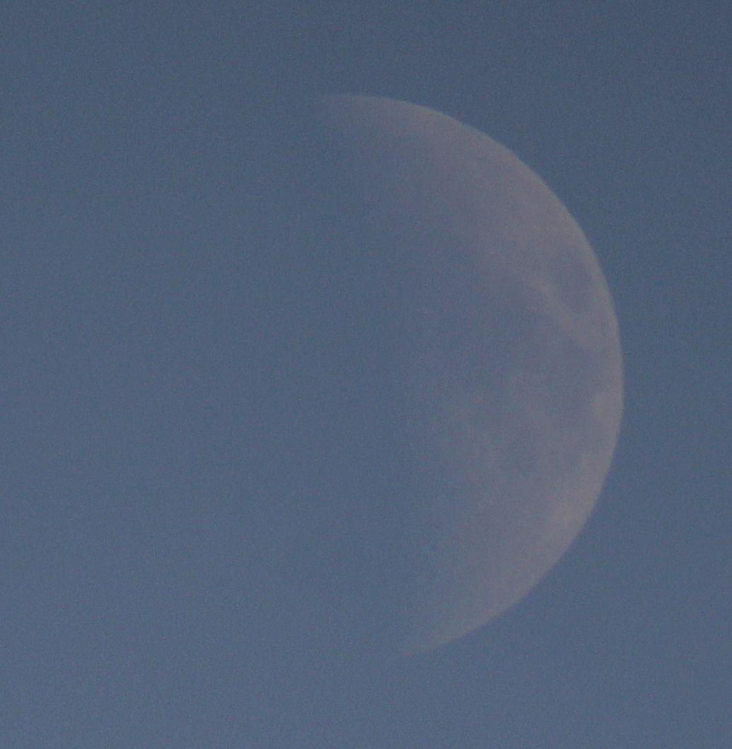 The Moon at waxing crescent phase on a blue sky background. 