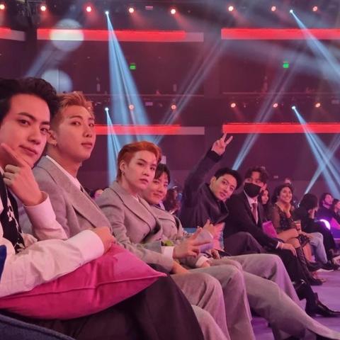 bts at an awards show, hyung line and their baby maknae. The hyungs look cool, the baby has his fingers in a victory sign above his head
