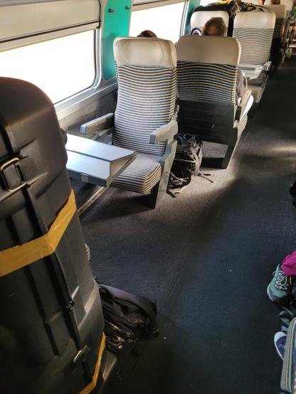 Another 2nd class wagon with only a pair of facing seats (and a larger corridor) at one point. A large luggage is next to these 2 seats.