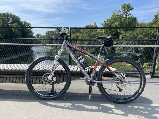 MTB auf einer Brücke, im Hintergrund ein Fluß mit bewaldeten Ufern