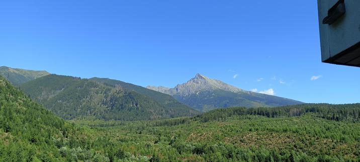 Forested hills in the foreground, a mountain with the top crooked to the left in the background, and a deep blue sky above it all. A bit of the hotel's balcony invades the picture in top right corner.