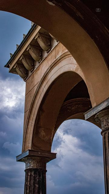 Arches and columns of portico of Church of the Redeemer with a dramatic cloudy sky in the background. Sacrow, Potsdam, 23 Jul 2024. Nikon D5600, Nikkor DX 35 mm ƒ1.8G, ISO 3600, ƒ22, -0.3 ev, 1/125s, polarizing filter