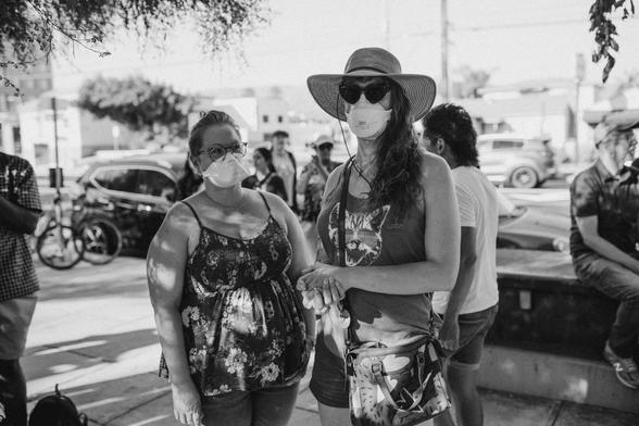 Black and white photo of my wife and me, masked, at the tag rally. We’re in tank tops and shorts as it was very hot. I’m wearing my large sun hat and heart shaped sunglasses 