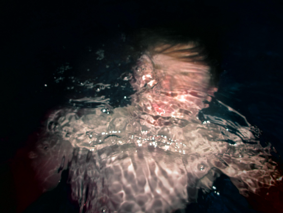 A person partially submerged in water (taken on a retro camera)