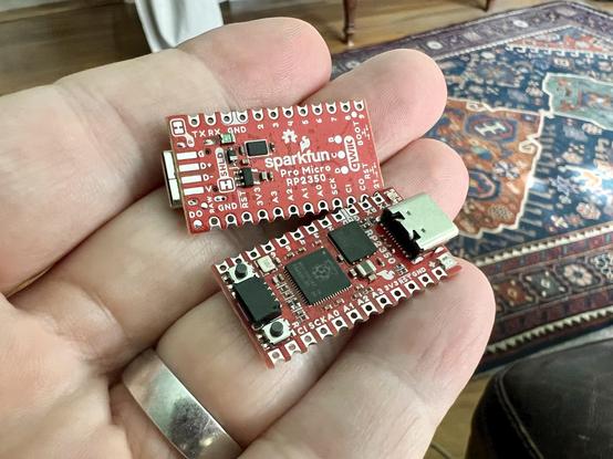 Close up of a hand holding two SparkFun RP2350 Pro Micro modules