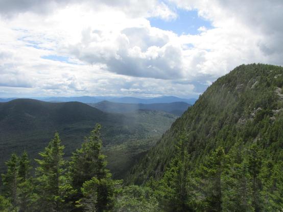 mountain view from top of Tumbledown showing distant hills, pine trees, and clouds