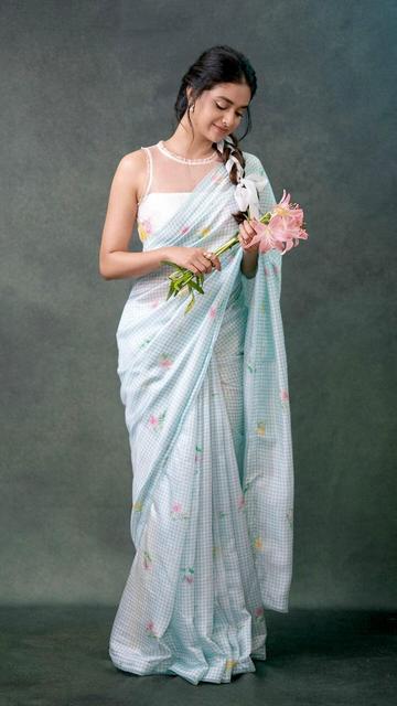 In a fashion-forward move, Keerthy Suresh dons a blue gingham saree paired with a chic sleeveless blouse, creating a look that's both stylish and sophisticated. The gingham print adds a playful element to the traditional saree, while the sleeveless blouse gives it a modern edge. Keerthy's natural grace and effortless style make this ensemble a showstopper. Perfect for anyone looking to blend tradition with contemporary fashion.