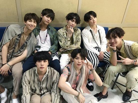 overhead shot of me and my crew (bts) members sitting on a tiny couch. We're wearing neutral colored clothing, and we all have black hair.