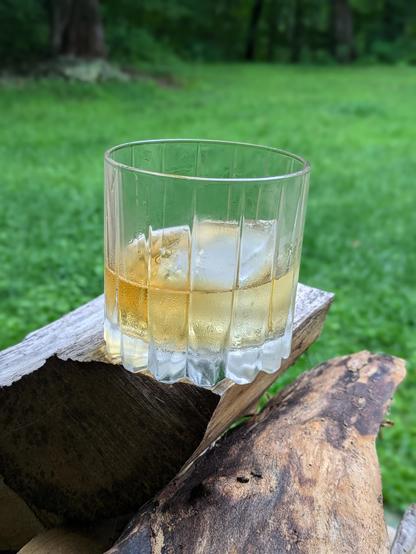 Two fingers of brown with a square cube.  Outside on the wood pile. It is Thursday, right?