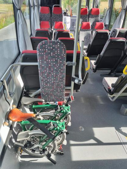 An empty bus with two folded folding bikes.
