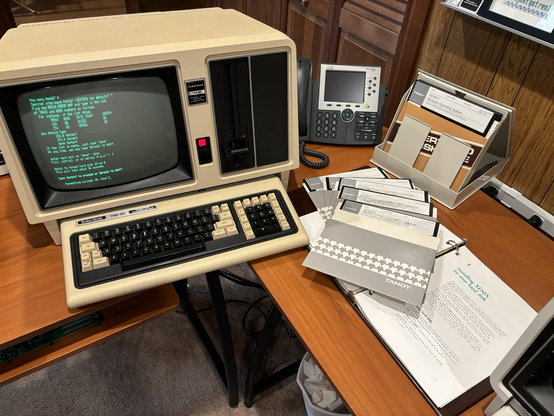 TRS-80 Model 16B computer, 8” XENIX installation diskettes, and user’s manual binder.