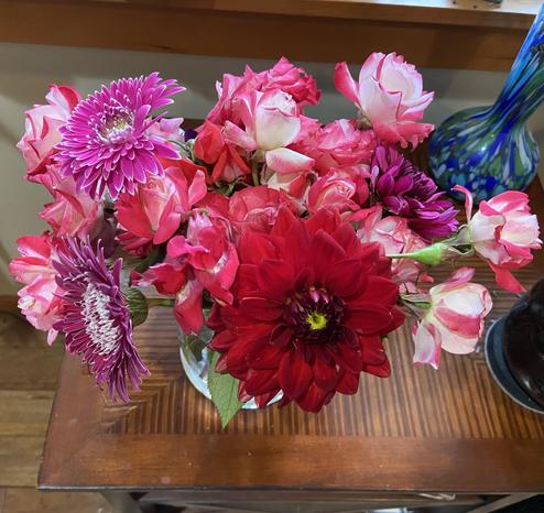 Pink and red flower bouquet of roses, dahlias and gerber daisy blooms on a brown table
