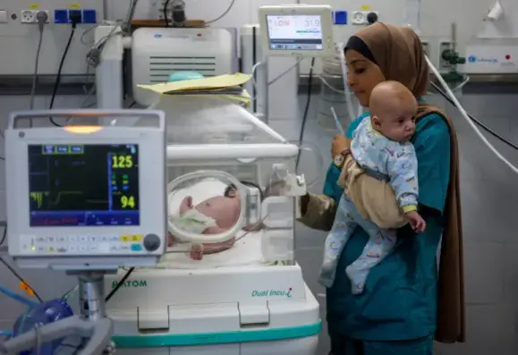 A nurse tending to a baby in an incubator holds a Palestinian infant at Al-Emirati hospital, in Rafah in the southern Gaza Strip, April 24, 2024 [File: Mohammed Salem/ Reuters]