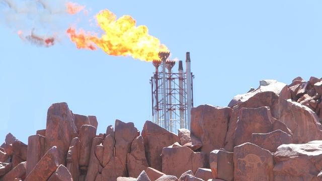 Gas being burned off at fossil fuel processing site amidst ancient rocks 40,000 + year old petroglyphs/rock carvings at Burrup Penisnula 