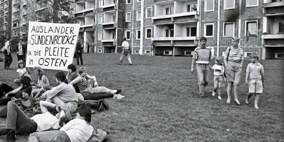 Rechte Demonstranten sitzen mit Banner in Rostock-Lichtenhagen vor dem Sonnenblumenhaus.