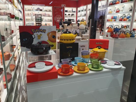 Display in a le creuset sites showing a pokémon themed cooking pan kettle, cups and plates. 