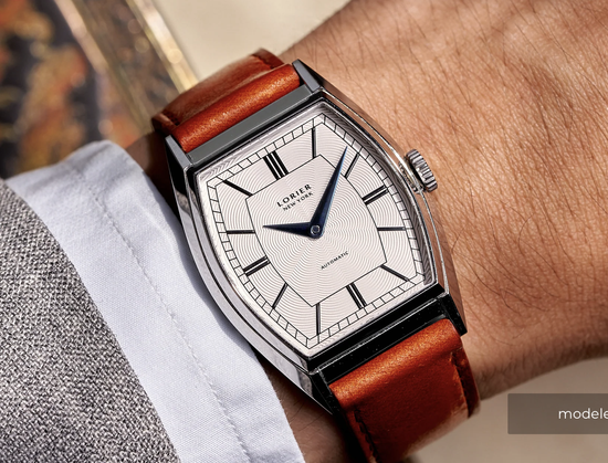 Product photo of the Zephyr watch on a brown strap on a wrist with shirt and suit cuff.