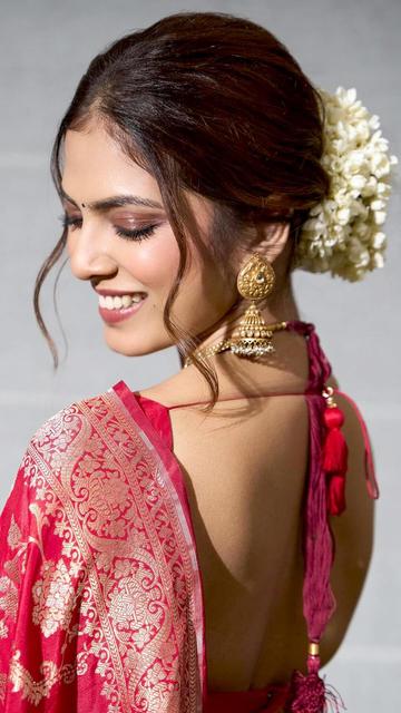 Malavika Mohanan has created waves across social media with her stunning appearance in a red Banarasi saree. This outfit, rich in cultural heritage, showcases intricate gold zari work that’s characteristic of Banarasi sarees. Malavika’s contemporary take on this traditional attire, with minimal jewelry and natural makeup, has made this look an internet sensation. The saree’s vibrant red hue perfectly complements her glowing complexion, making this look a perfect blend of elegance and modernity. Catch this viral moment now!