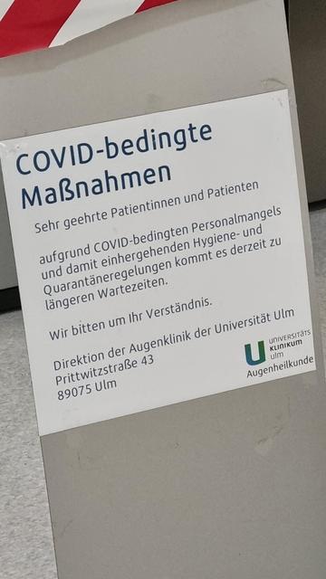 Ein Hinweisschild in einer Augenklinik: Darauf wird um Verständnis für lange Wartezeiten aufgrund "COVID-bedingten" Personalmangel gebeten.