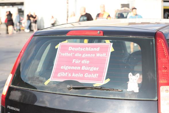 Plakat mit der Aufschrift "Deutschland Retter die ganze Welt. Für die eigenen Bürger gibt's kein Geld".