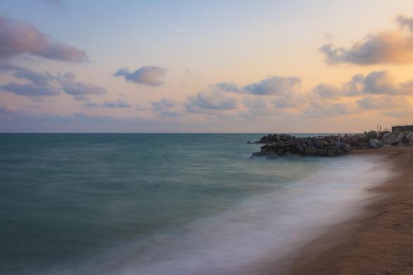 Fotografía de una playa al final de la tarde con el mar en larga exposición.