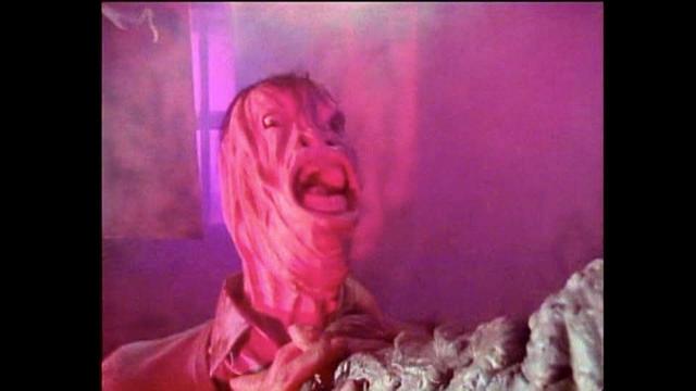 A distorted, ghastly figure expressing fear or horror, surrounded by a foggy, colorful atmosphere with purple and pink hues.