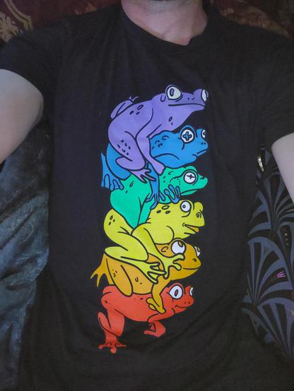 A shirt with a picture of a pile of rainbow colored frogs