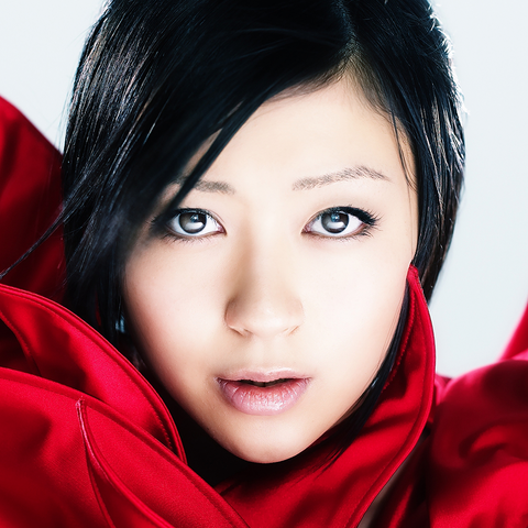 a head shot of Hikaru Utada staring directly ahead. They have glossy medium length black hair and are wearing a red coat that is flowing around them