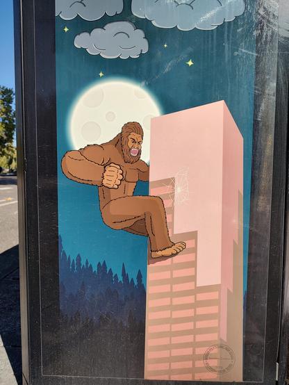 A giant Bigfoot climbing, and punching, a large office building in Portland. Commonly known as Big Pink, the building has a crack where the Bigfoot has punched it. The full moon is behind the Bigfoot, there are some clouds and stars overhead. This is all a reference to the old Arcade game named Rampage. What isn't quite show is that the art is on the side of a public trash can