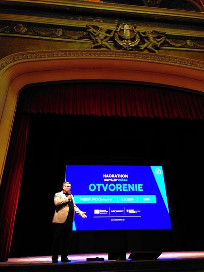 P. Oľha pri otvoreni 2. hackathonu zo serie Hacknime.to v Presove. P. primátor stojí na javisku v PKO Čierny orol.