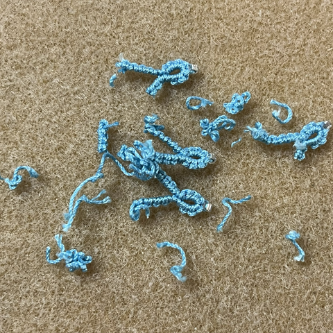Cut up bits of light turquoise blue tatting that didn’t work out, a byproduct of designing.