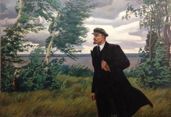A painting of Vladimir Lenin in a suit, black coat, and hat standing in an open field next to some trees and shrubs. This painting was made by Kokhal Vladimir Vladimirovich (born 1941) and is called "Lenin in Razliv," made in 1974.