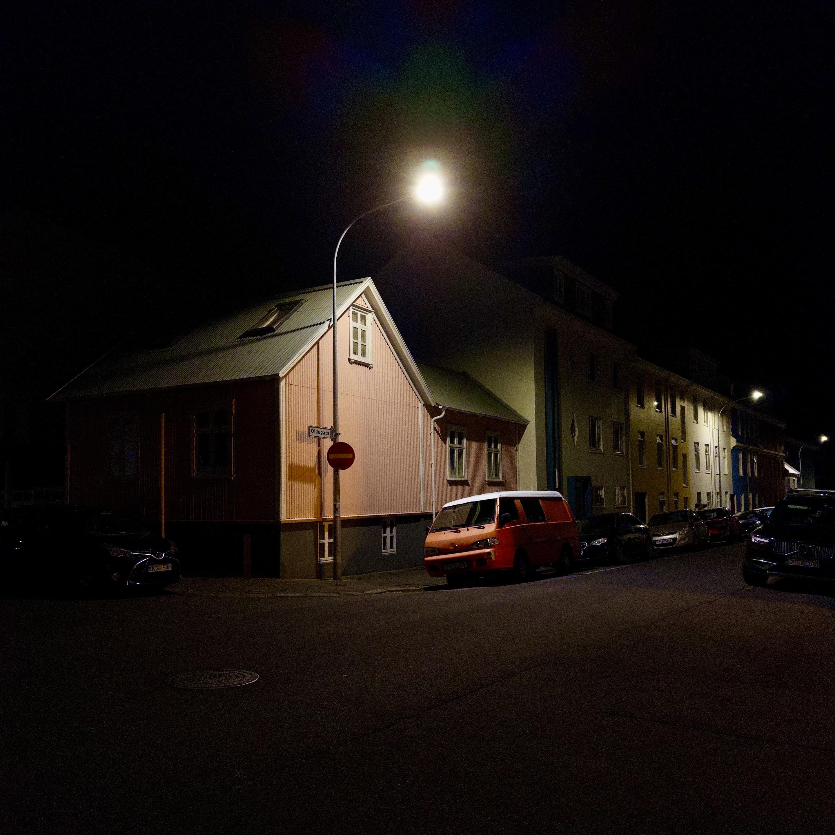 The pink house on Öldugata at night with an orange-ish Hyundai van parked out front