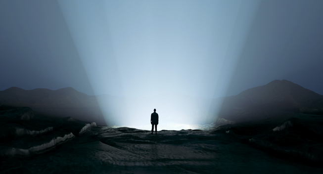 Silhouette in dark landscape with a light ray 