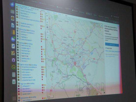 Osmose (an OpenStreetMap validation tool) is displayed on a screen during a presentation. The left side of the screen shows a list of mapping issues, including broken highways, duplicate geometry, and bad tags, marked with different colored dots indicating their severity. The right side of the screen shows a map of Nairobi, Kenya, with roads and various markers, highlighting areas needing attention.