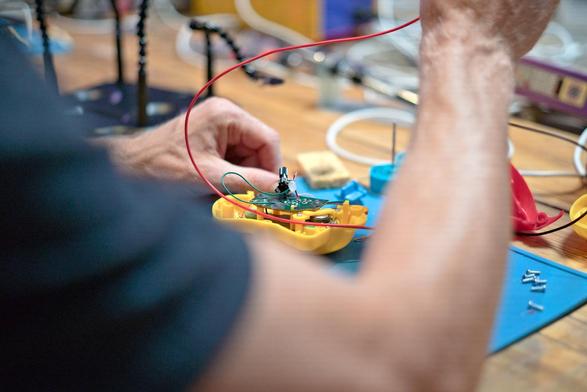 looking over the shoulders of someone who has just dismantled an electric children's toy and is soldering on it