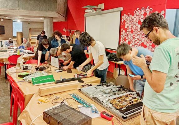 xente colaborando nun repair café, reparando diferentes aparatos