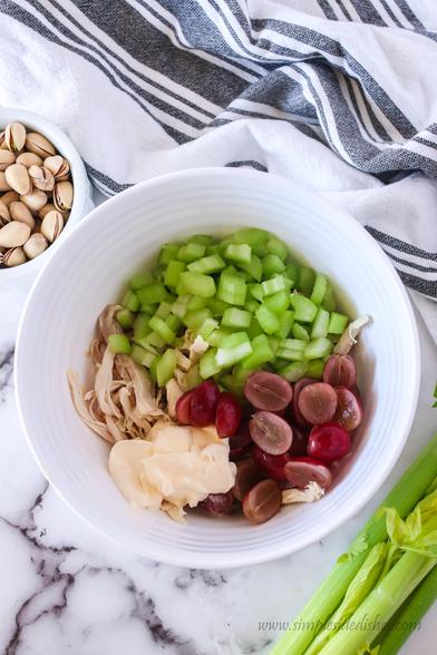 Celery, grapes, chicken and mayo in a bowl, unmixed. 