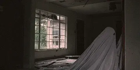 Animated gif.
A ghost ( a person covered in a white sheet) look at a window being destroyed by a power shovel. He raised scared.
From the movie: A Ghost Story