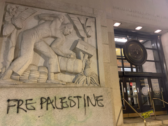 “Free Palestine” spray painted in black under a sculpture next to the fancy govt building entrance to the US Post Office and Passport Office in center city Philadelphia